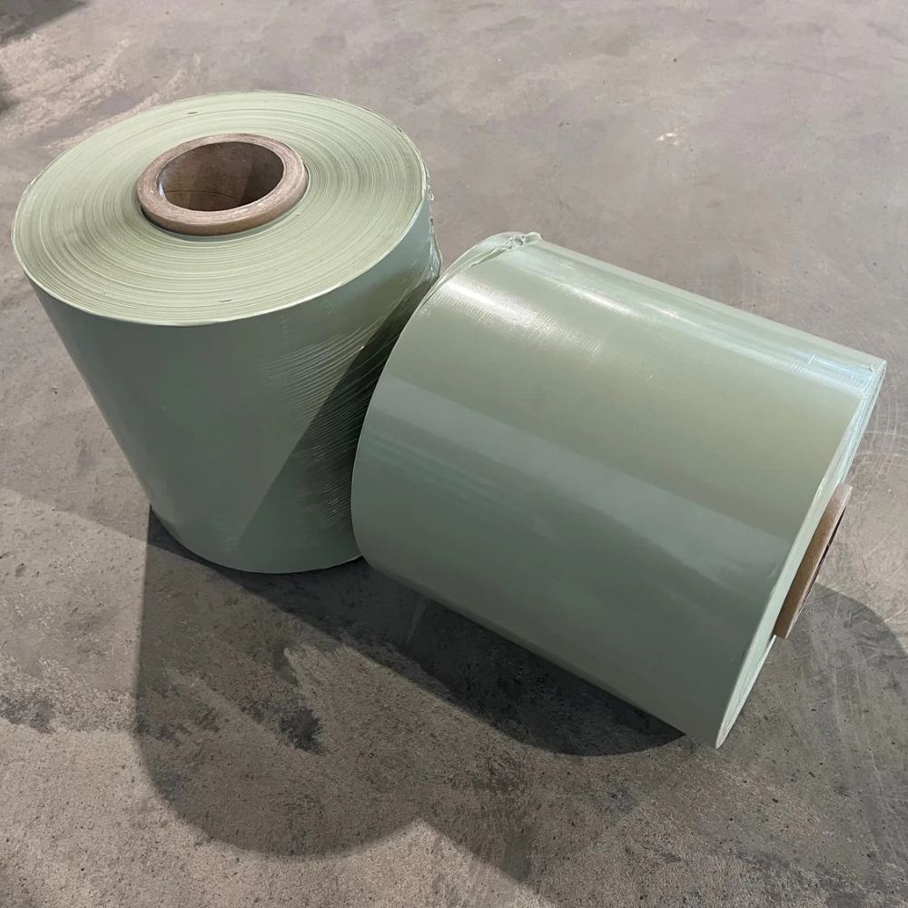 Rullar med grön balplast anpassad för CAEB Mountainsilo, liggande på golv.