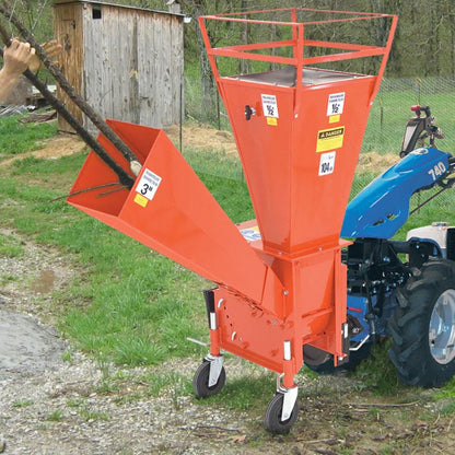 Caravaggi BIO 100 flishugg i bruk där en person matar in grenar för effektiv flisning av trädgårdsavfall.