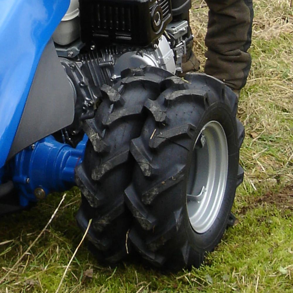 Tvåhjulstraktor med dubbelmontage i bruk under fältarbete för bättre grepp och dragkraft.