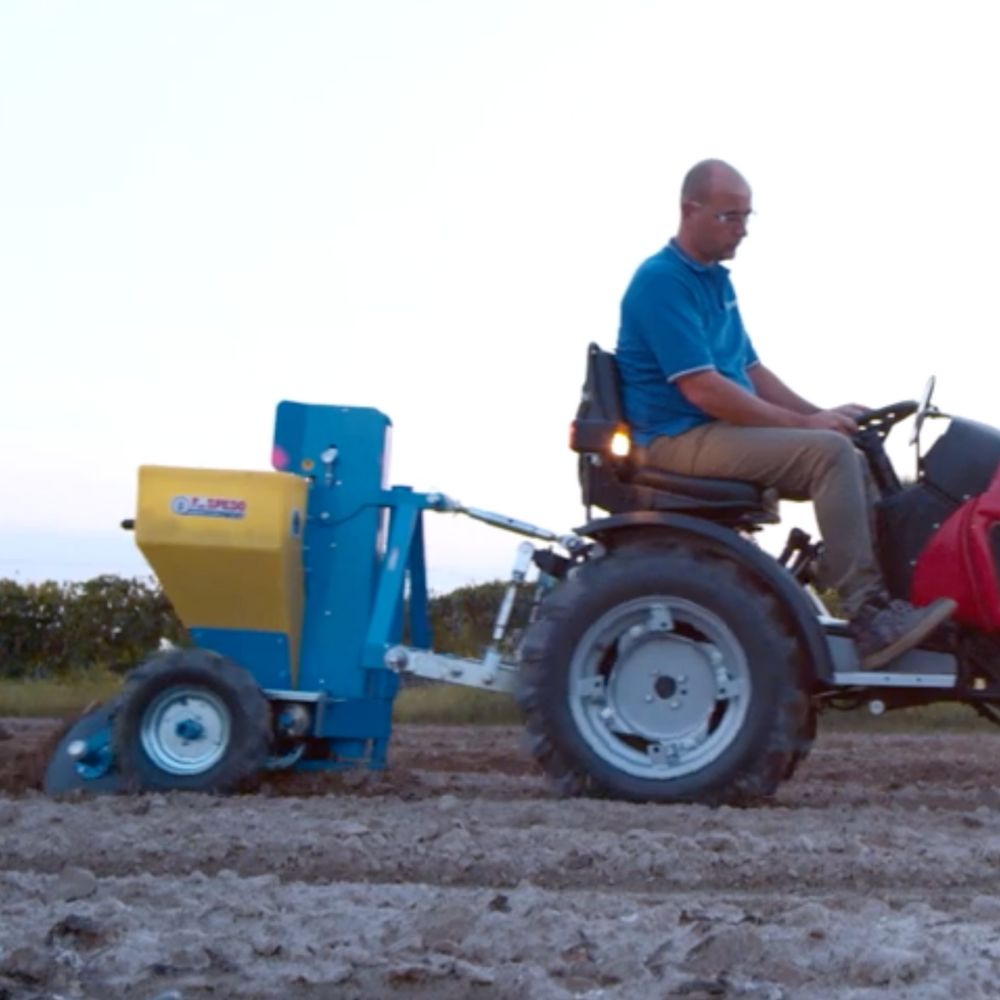 Sidovy av F.lli Spedo potatissättare monterad på en traktor som sätter potatis i fält.