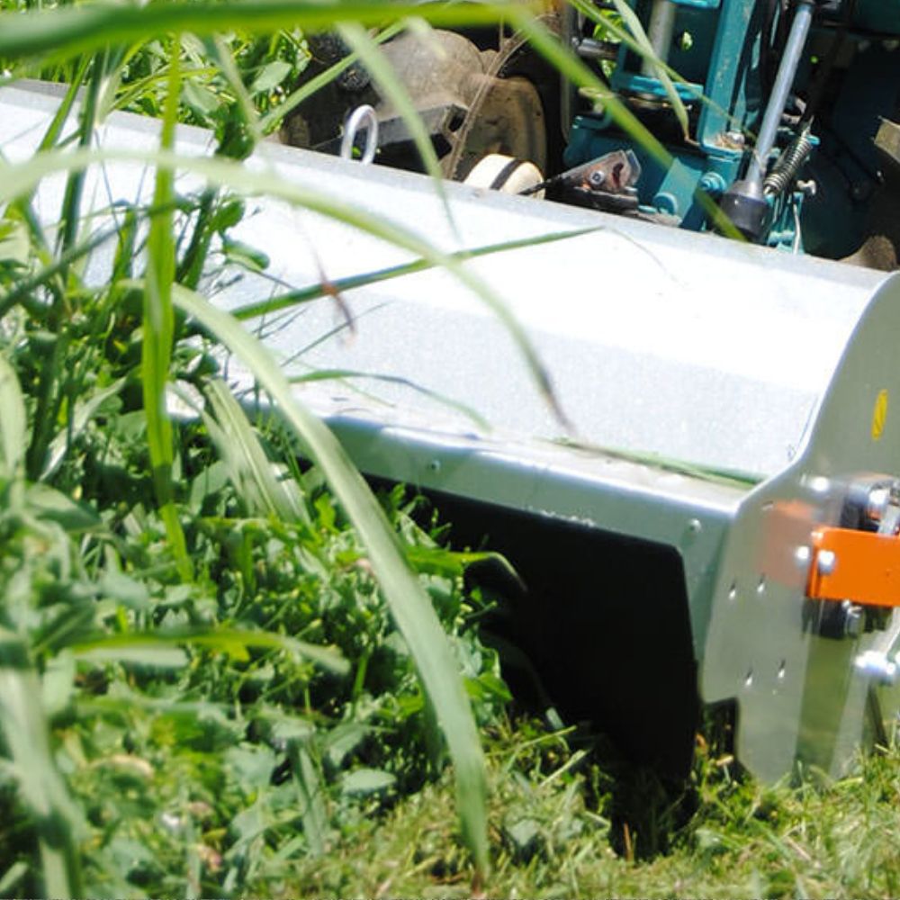Klippning av högt gräs med slagklippare Bertolini Flail Mower monterad på tvåhjulstraktor, närbild under arbete.