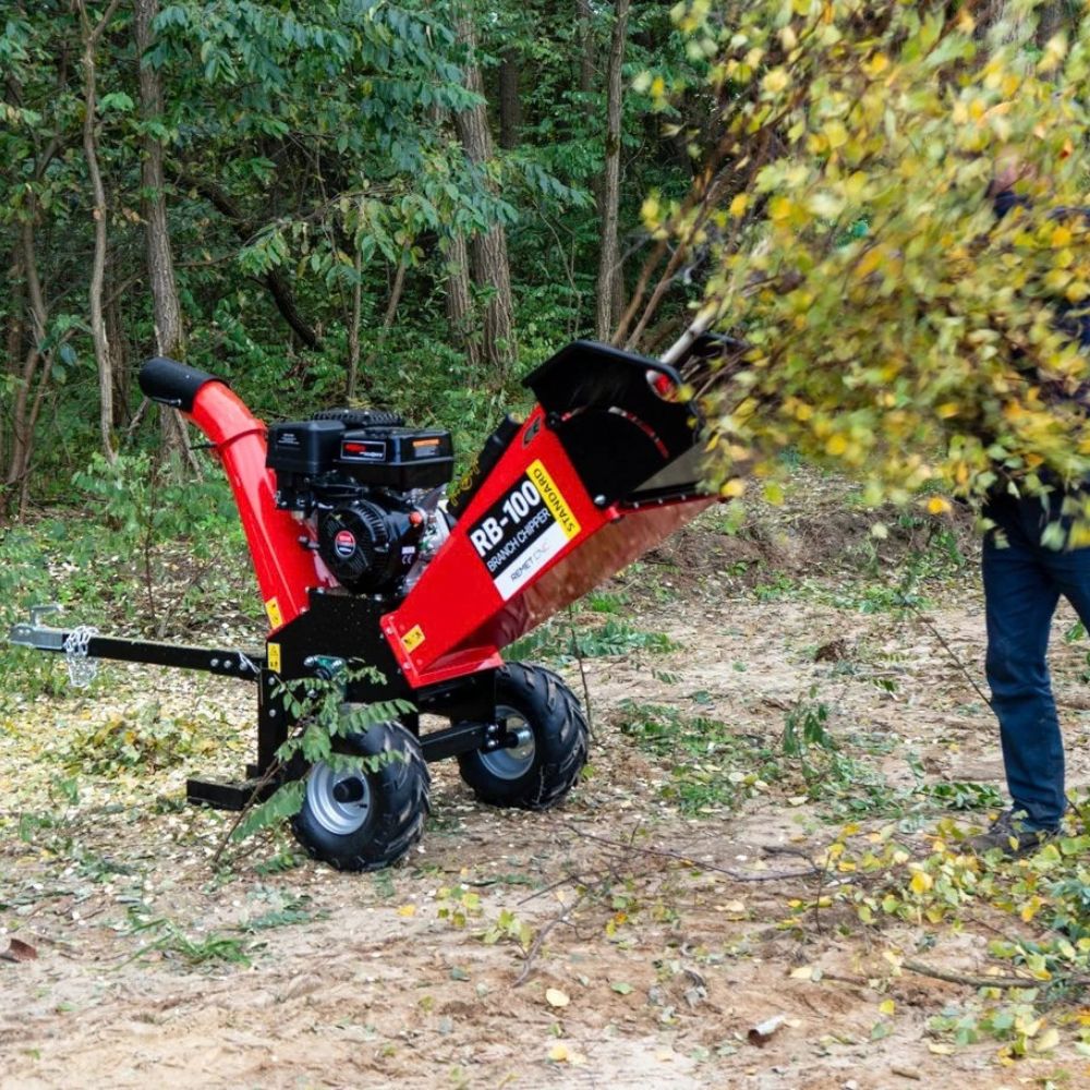 En användare matar in lövklädda grenar i den mobila bensindrivna flishuggen Remet RB-100.