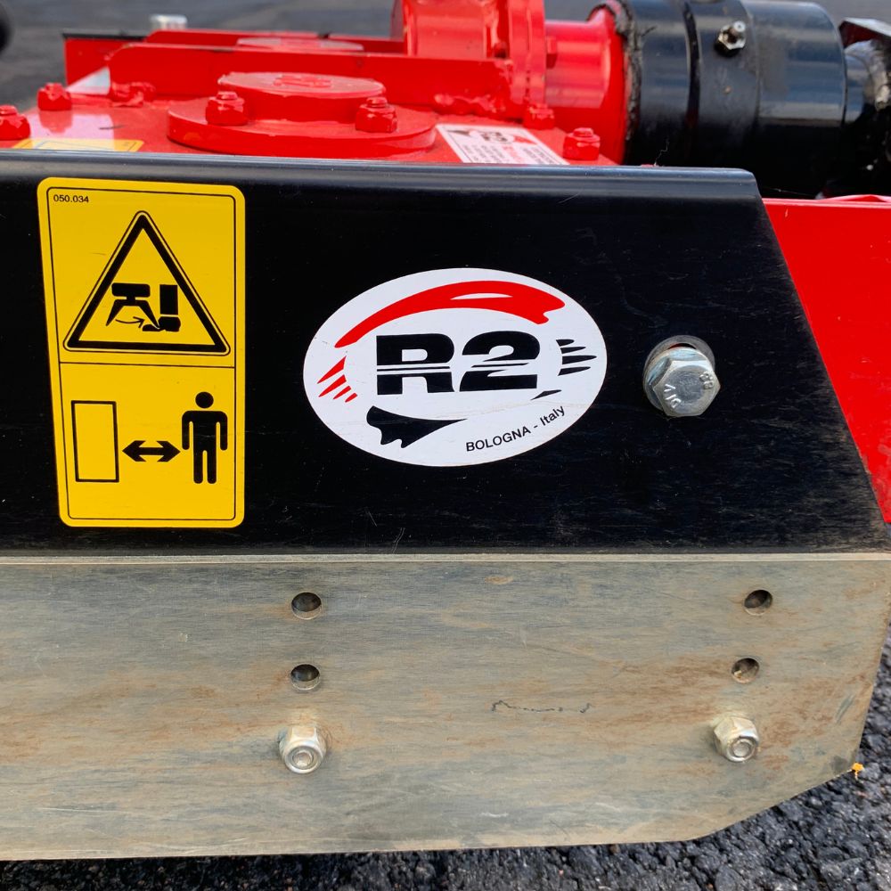Närbild på R2-logotyp och säkerhetsmärkning på Rinaldi MTL 50 rotorharv med gallervält